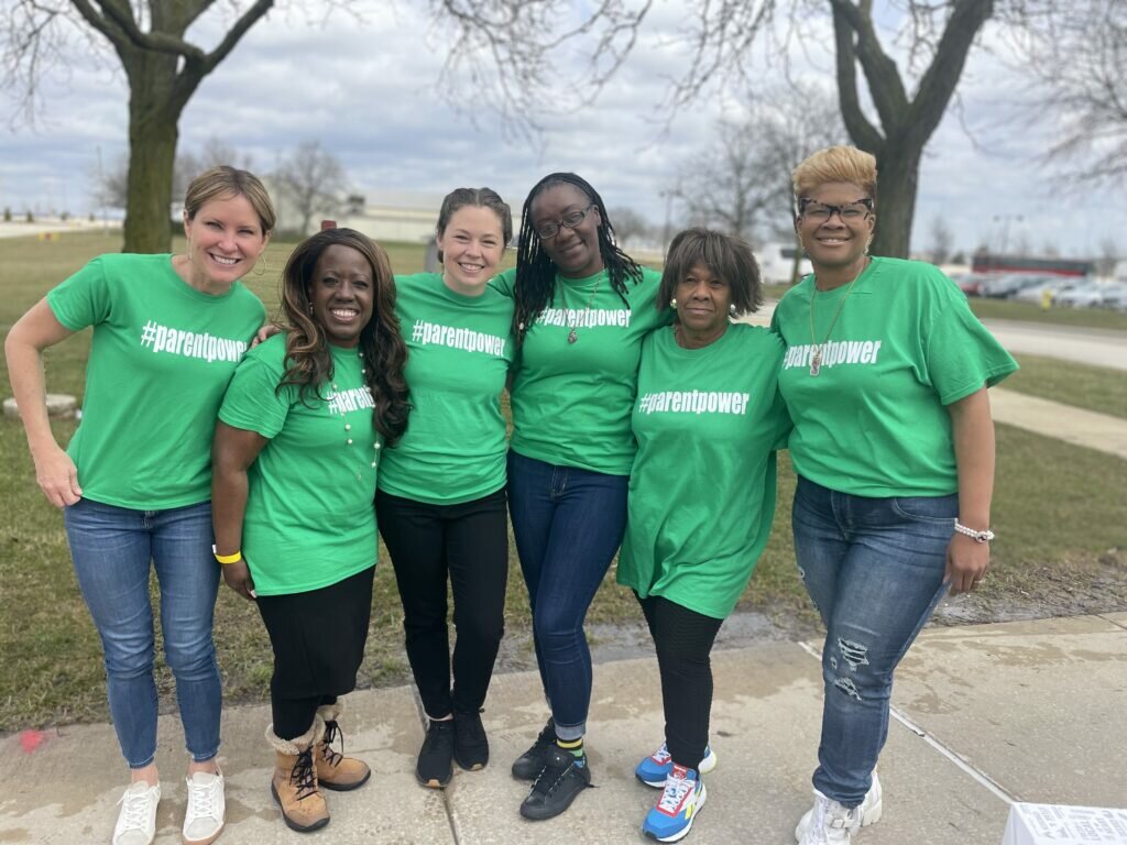 Brittany Kinser poses next to a group of women wearing green t-shirts with the word 
