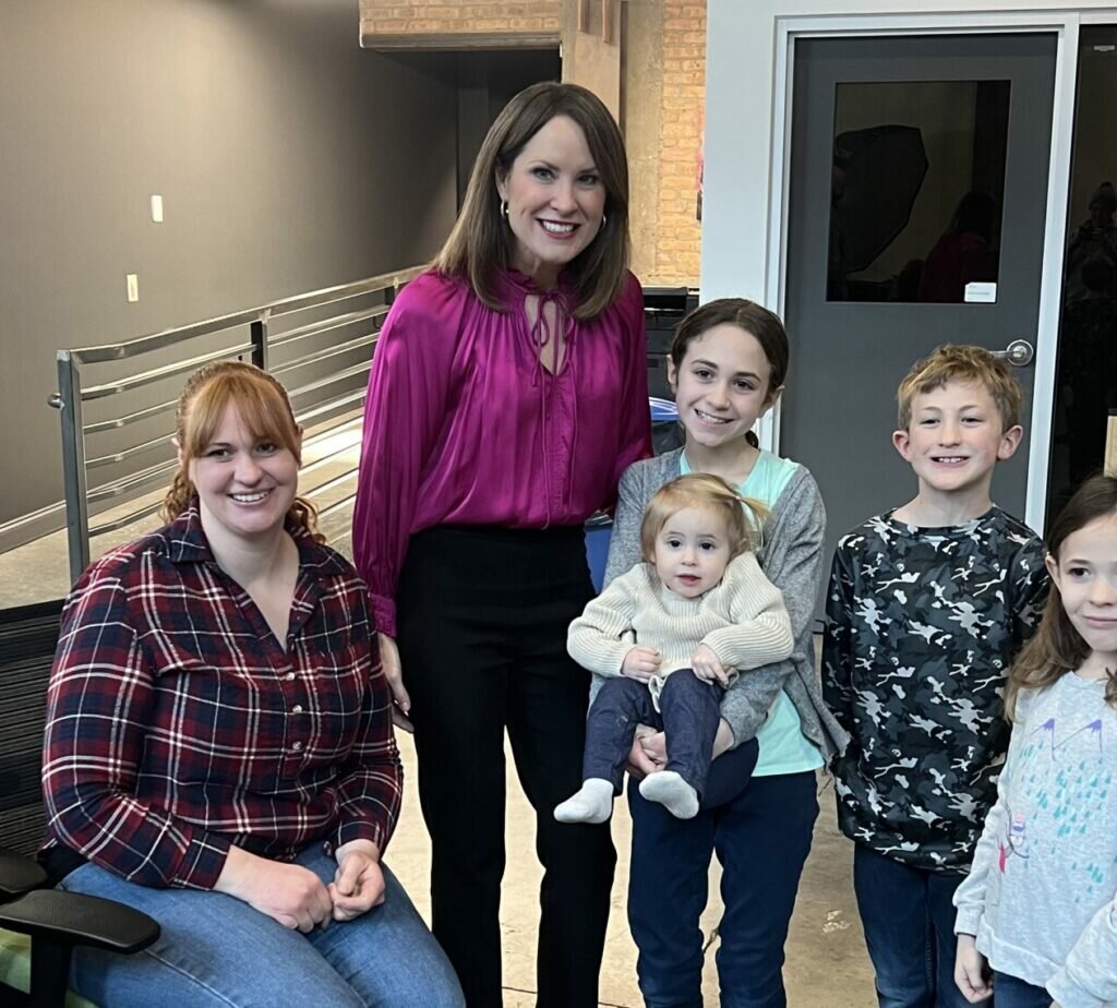 Brittany Kinser poses next to kids and educator.